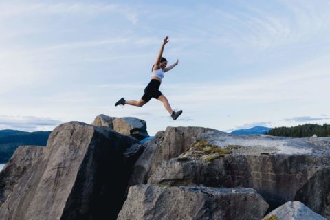 Femme sautant sur les rochers au somment d'une montagne - Blogue - Les obstacles au développement durable | Marie-Andrée Roy, Services conseil et Design Thinking
